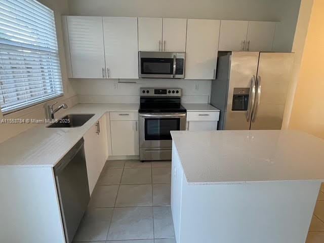 kitchen with white cabinetry, sink, stainless steel appliances, and light tile patterned flooring