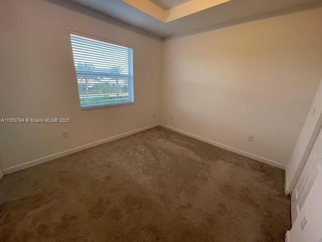 empty room featuring dark carpet and a tray ceiling