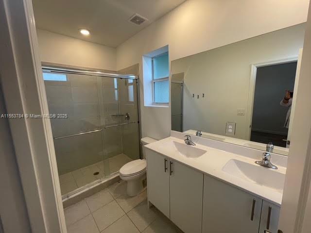 bathroom featuring vanity, a shower with shower door, tile patterned floors, and toilet