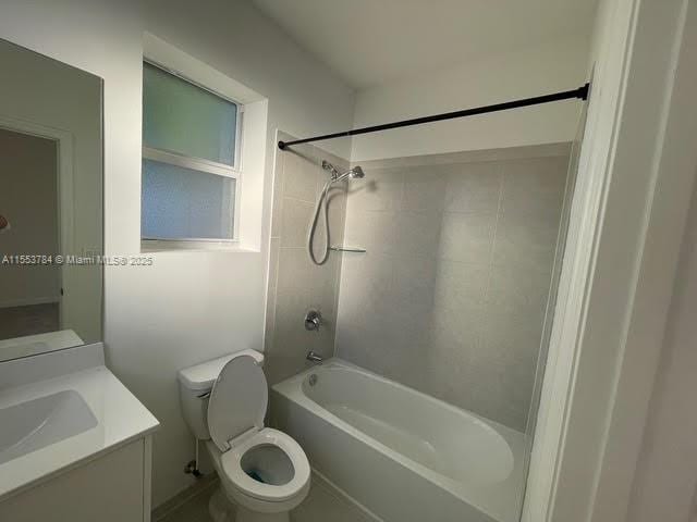 full bathroom with tiled shower / bath, vanity, and toilet