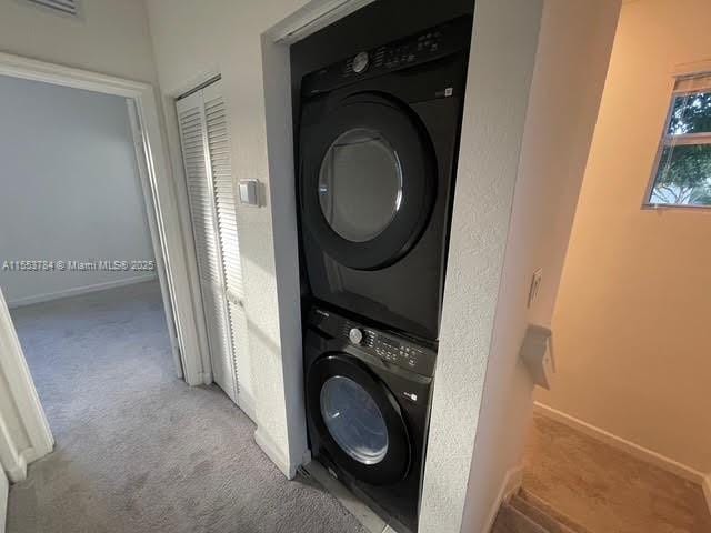 laundry room with stacked washer and dryer and light colored carpet