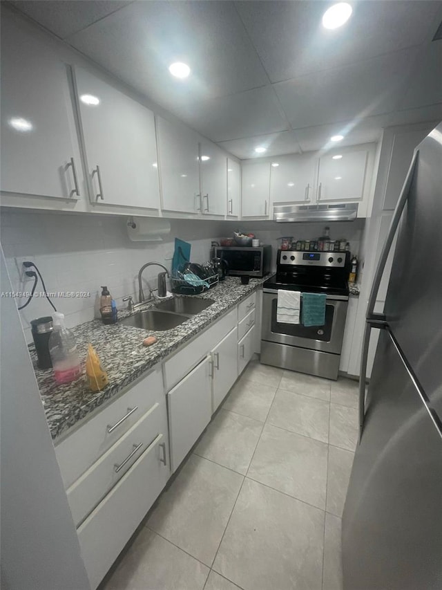 kitchen featuring sink, light tile floors, white cabinets, appliances with stainless steel finishes, and stone counters