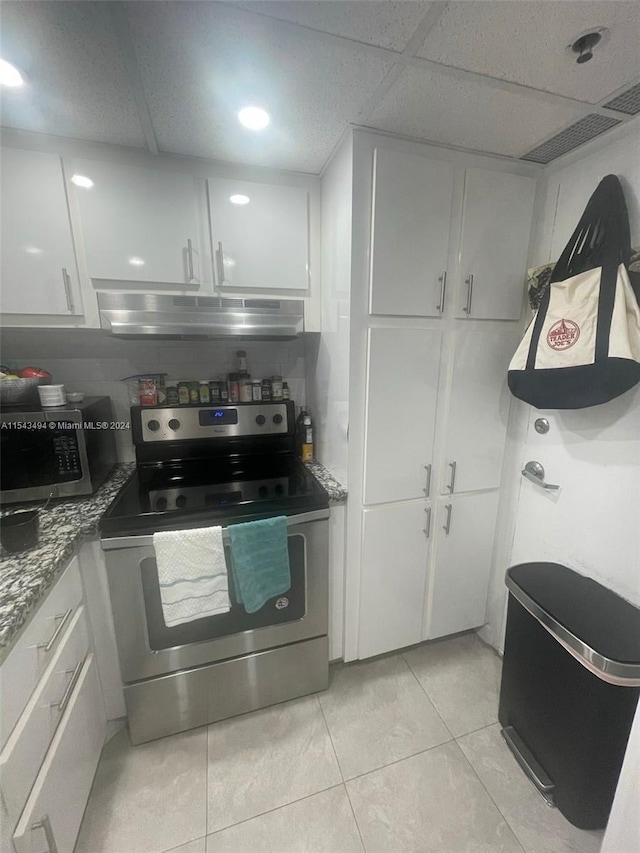 kitchen featuring light tile flooring, a drop ceiling, appliances with stainless steel finishes, and white cabinetry