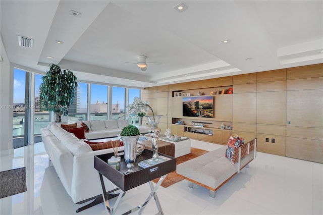 tiled living room featuring ceiling fan and a tray ceiling