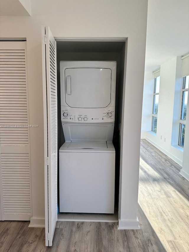 laundry room with stacked washer / drying machine and hardwood / wood-style floors