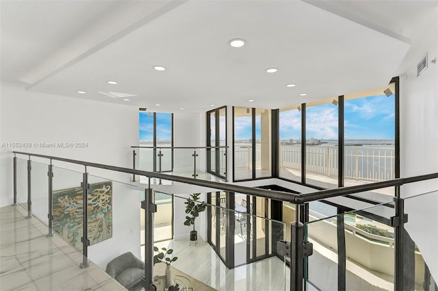 corridor with light tile floors and a wall of windows