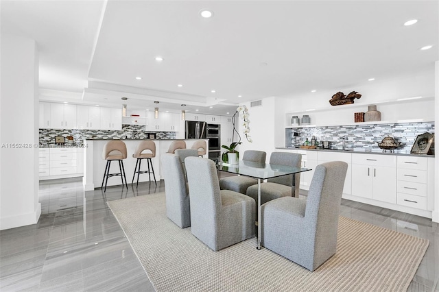 dining room featuring light tile flooring, a tray ceiling, and sink