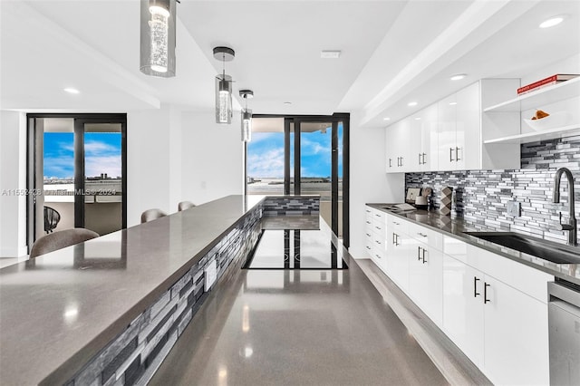 kitchen with white cabinetry, backsplash, sink, and pendant lighting