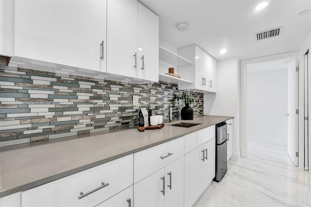 kitchen with white cabinets, tasteful backsplash, light tile floors, and sink