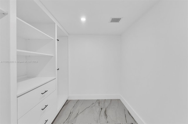 walk in closet with light tile floors