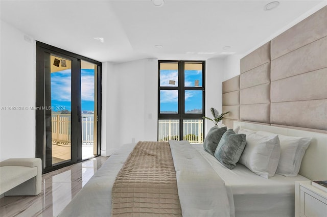 bedroom featuring multiple windows, floor to ceiling windows, and access to exterior