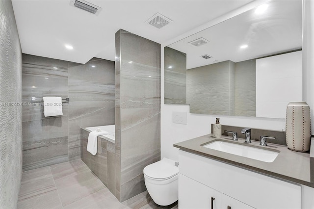 bathroom featuring tile flooring, tile walls, toilet, vanity, and a bathing tub