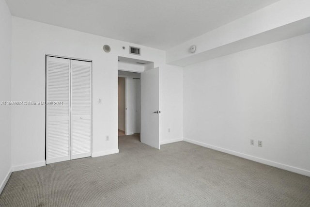 unfurnished bedroom with light colored carpet and a closet