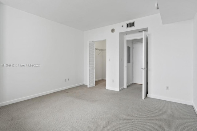 unfurnished bedroom featuring light colored carpet, a spacious closet, and a closet