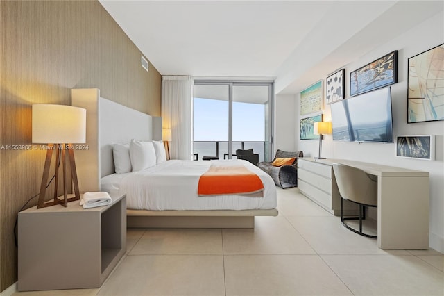 bedroom featuring a wall of windows and light tile floors