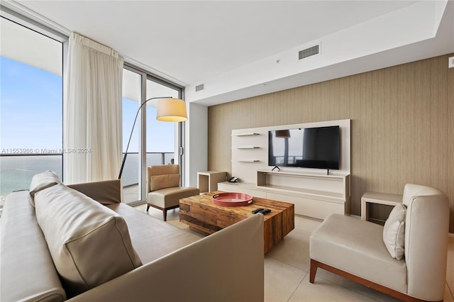 living room featuring a water view, expansive windows, and light tile floors