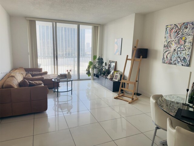 living room with expansive windows, a textured ceiling, and light tile patterned flooring