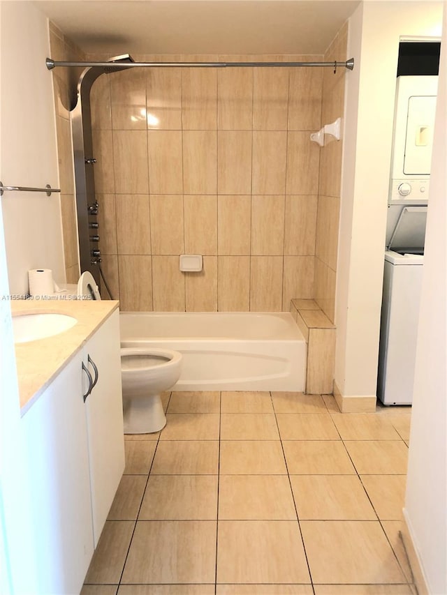 full bathroom featuring stacked washer / dryer, tiled shower / bath combo, vanity, tile patterned flooring, and toilet