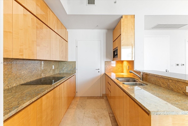 kitchen with light tile floors, light stone countertops, tasteful backsplash, and sink