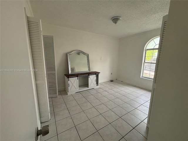 interior space with light tile patterned floors, baseboards, and a textured ceiling