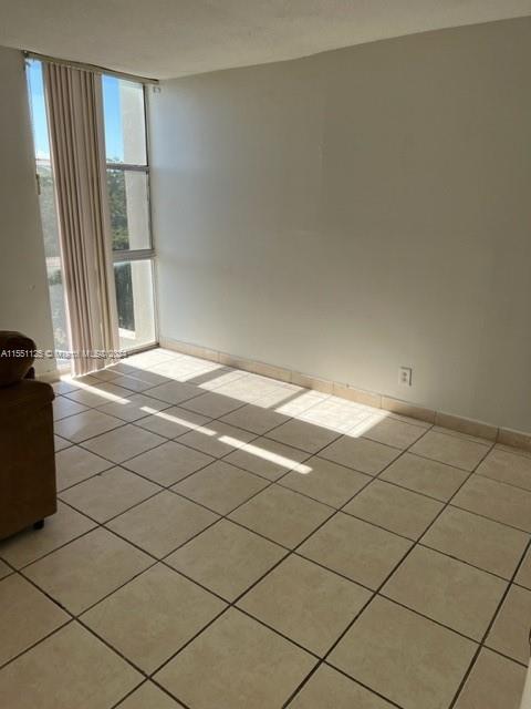 tiled empty room featuring a wall of windows