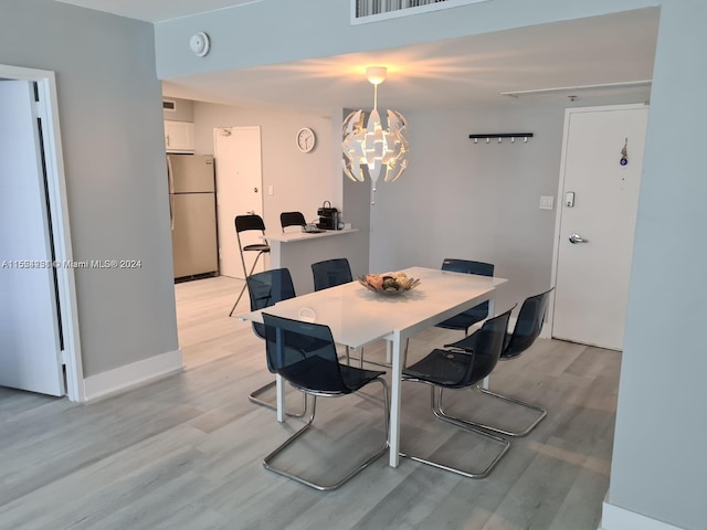 dining area featuring light hardwood / wood-style floors and an inviting chandelier