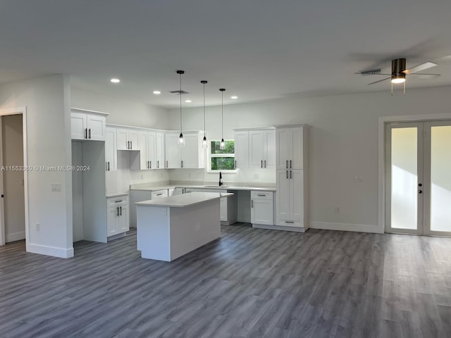 kitchen featuring dark wood-type flooring, ceiling fan, white cabinets, a center island, and pendant lighting