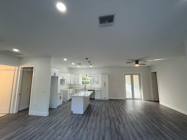 kitchen with hanging light fixtures, ceiling fan, sink, white cabinets, and a kitchen island