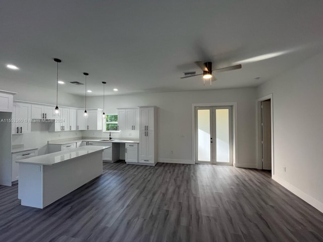 kitchen with ceiling fan, white cabinets, dark wood-type flooring, decorative light fixtures, and a center island