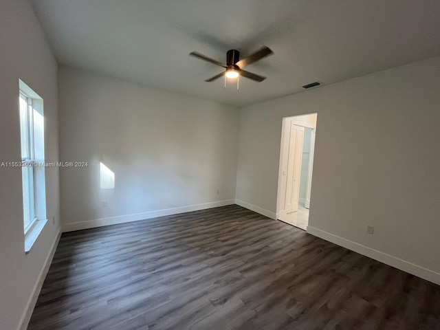 empty room with plenty of natural light, ceiling fan, and dark hardwood / wood-style flooring