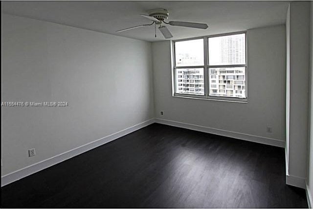 spare room featuring ceiling fan and dark wood-type flooring