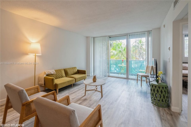 living room featuring a textured ceiling, light hardwood / wood-style floors, and a wall of windows