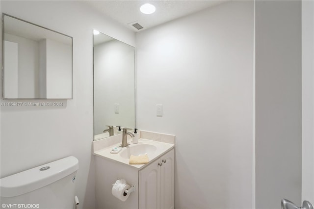 bathroom featuring toilet, a textured ceiling, and vanity