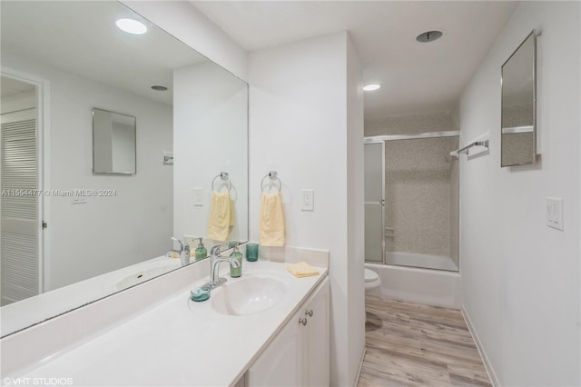 full bathroom featuring toilet, hardwood / wood-style floors, vanity, and bath / shower combo with glass door