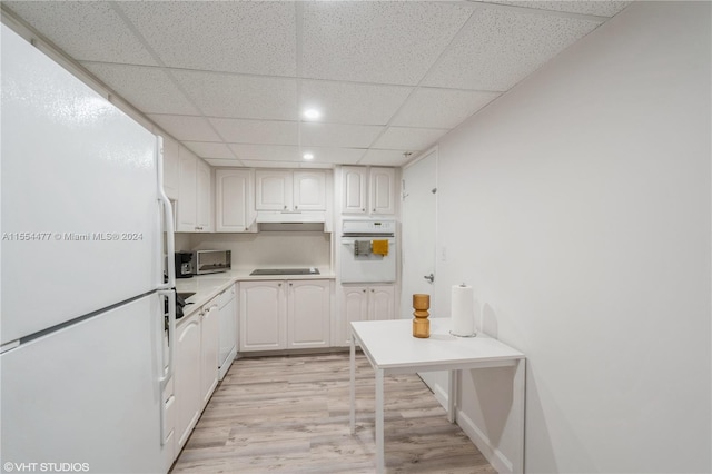 kitchen with white appliances, white cabinetry, light hardwood / wood-style floors, and a drop ceiling