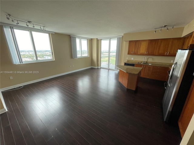 kitchen with a center island, sink, dark hardwood / wood-style floors, a textured ceiling, and stainless steel refrigerator