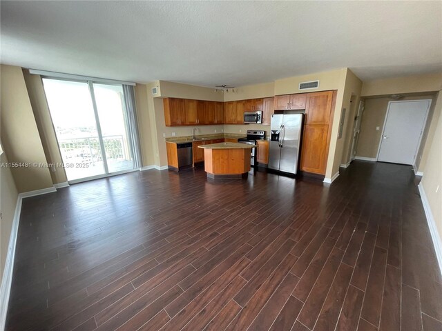 kitchen with sink, a kitchen island, dark hardwood / wood-style floors, and appliances with stainless steel finishes