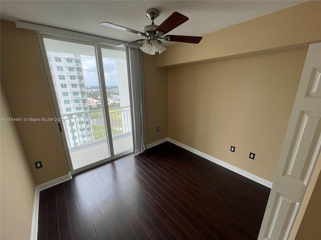 empty room with floor to ceiling windows, ceiling fan, and dark hardwood / wood-style floors