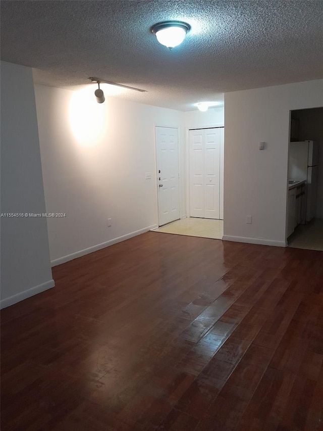 spare room featuring a textured ceiling and dark hardwood / wood-style floors