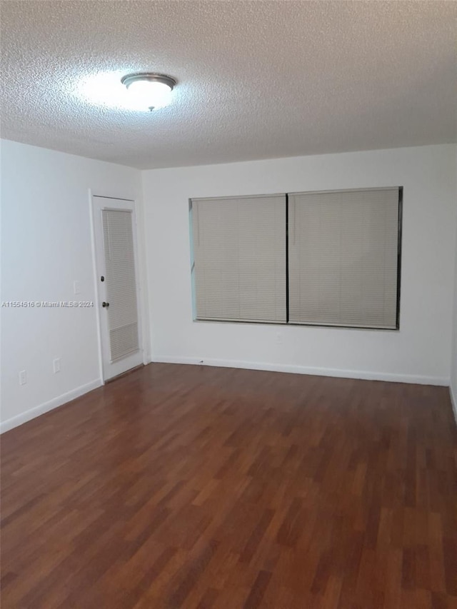 spare room with dark hardwood / wood-style floors and a textured ceiling