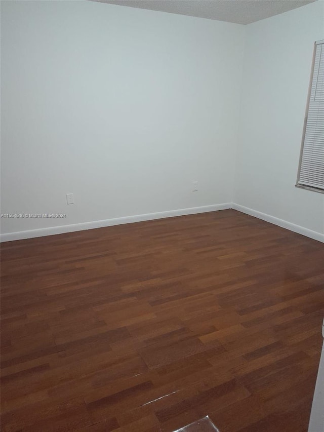 spare room featuring dark hardwood / wood-style floors and a textured ceiling