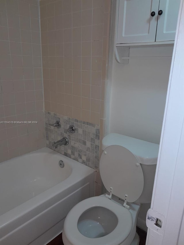 bathroom featuring toilet and tiled shower / bath