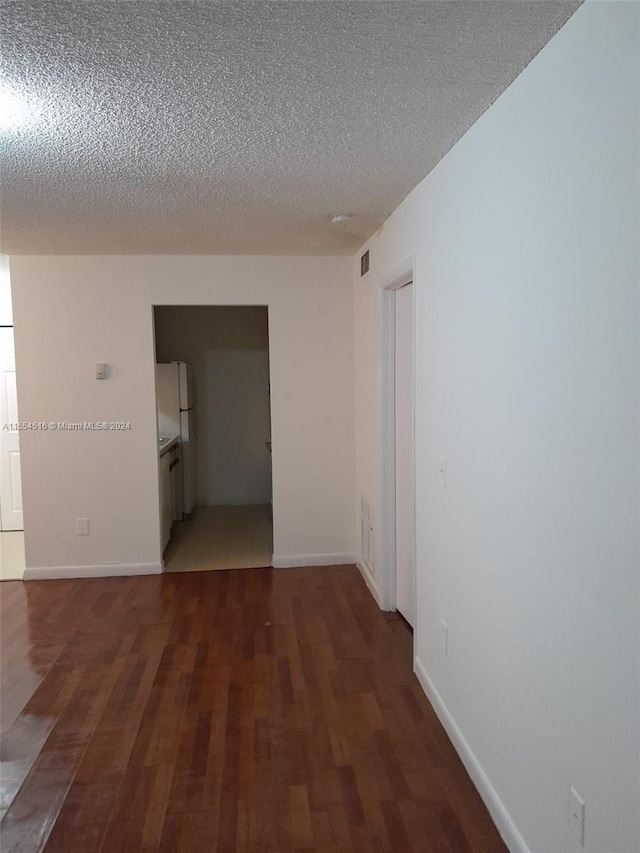 spare room with a textured ceiling and dark hardwood / wood-style floors