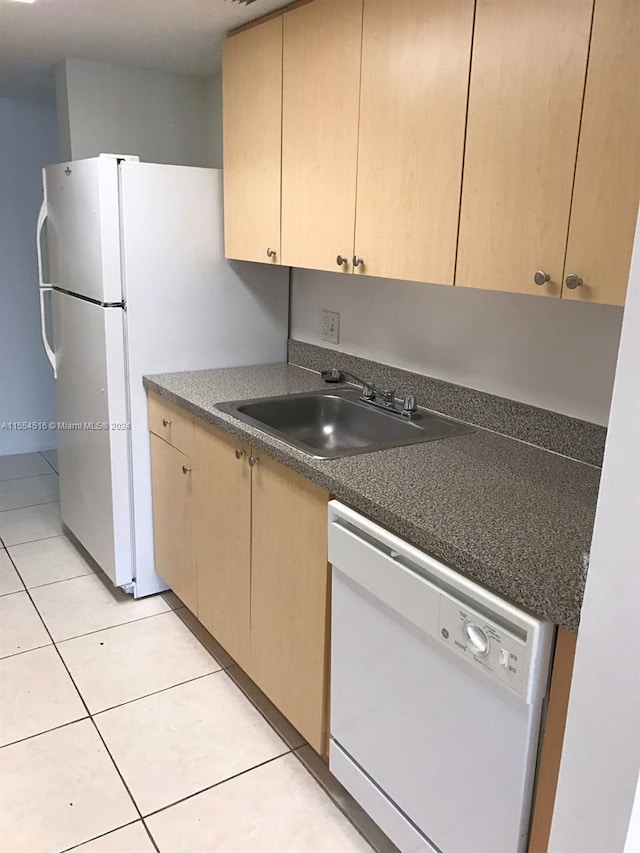 kitchen with light tile floors, light brown cabinets, white dishwasher, and sink