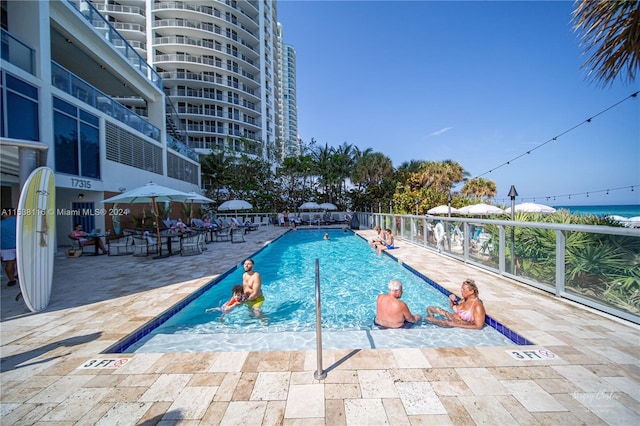 view of swimming pool featuring a patio and a water view