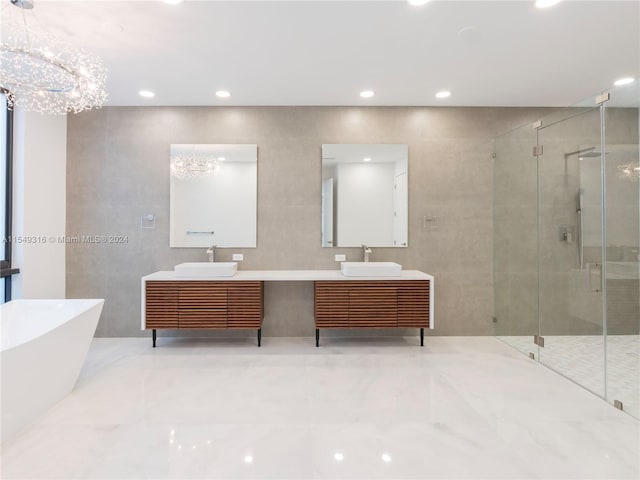 bathroom featuring shower with separate bathtub, a notable chandelier, oversized vanity, and double sink