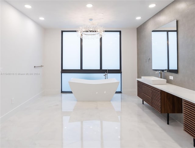 bathroom featuring tile floors, a notable chandelier, vanity, a healthy amount of sunlight, and a bathtub