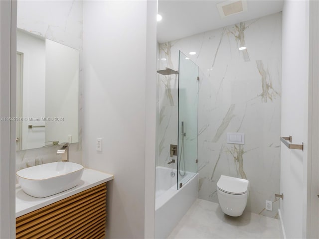 full bathroom with bath / shower combo with glass door, tile flooring, toilet, vanity, and tile walls