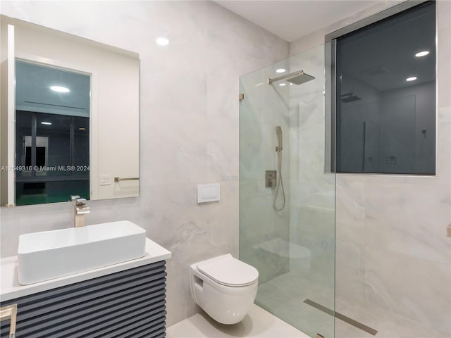 bathroom with tile walls, toilet, vanity, and a shower with door