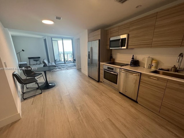 kitchen with light hardwood / wood-style floors, appliances with stainless steel finishes, and sink